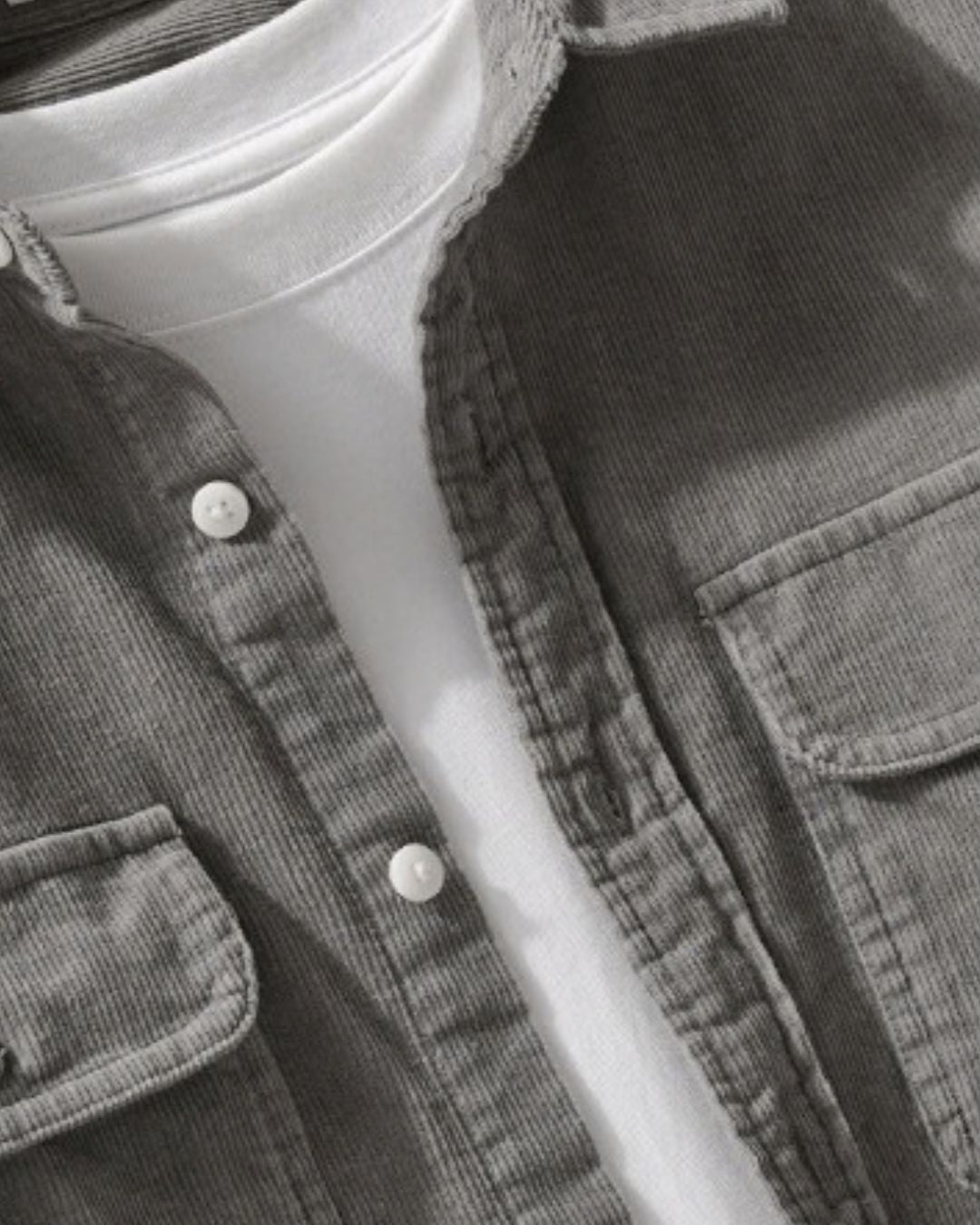 Grey cotton corduroy button-up shirt with chest pockets worn open over a white t-shirt.