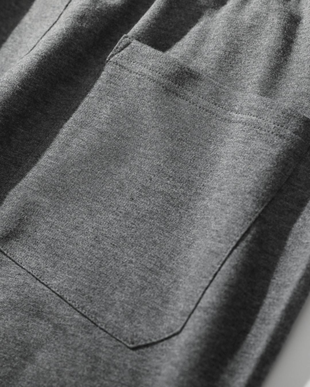 Close-up of soft, grey cotton jogger sweatpants featuring a deep side pocket and comfortable, washed fabric texture.