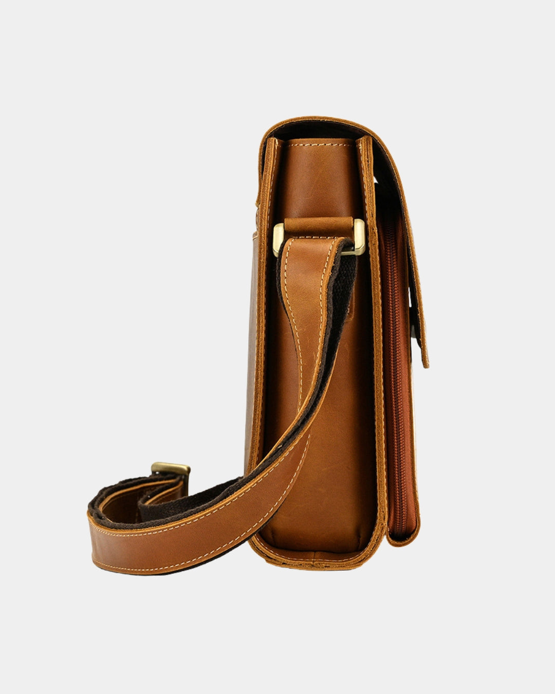 A brown leather crossbody bag shown from the side profile, featuring a matching leather strap with gold-tone metal hardware, set against a plain light gray background.
