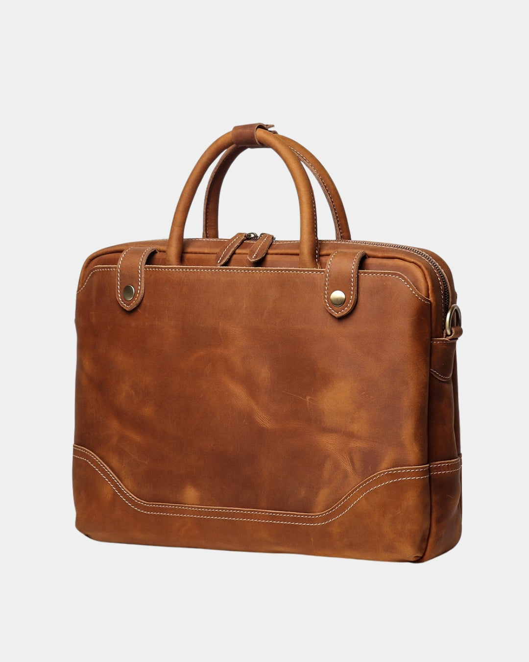 A cognac brown distressed leather briefcase with dual top handles, brass-tone hardware, and contrast stitching, shown on a light gray background.