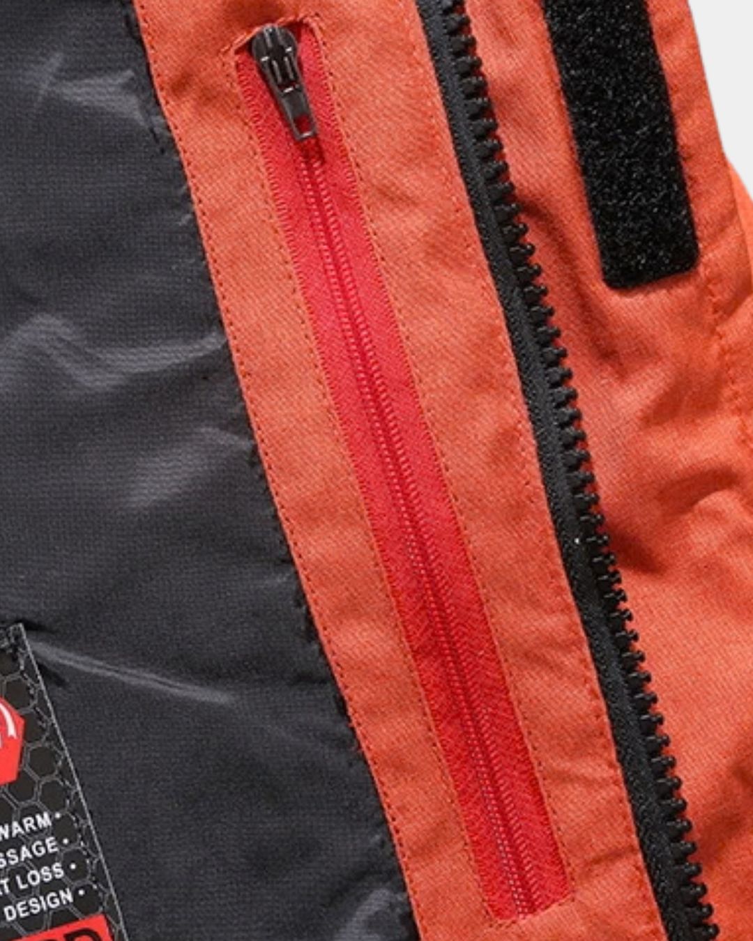 Close-up of an orange and black puffer ski jacket featuring a secure vertical zip pocket and durable front zipper closure.