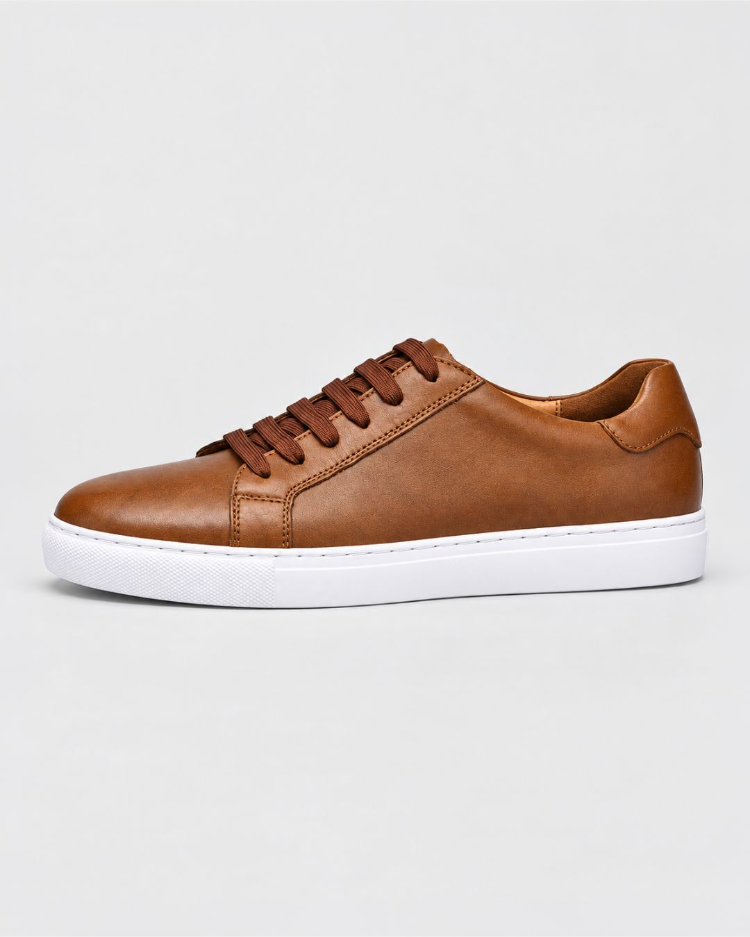 Cognac brown top-grain leather low-top dress sneaker with matching laces and a clean white rubber outsole.
