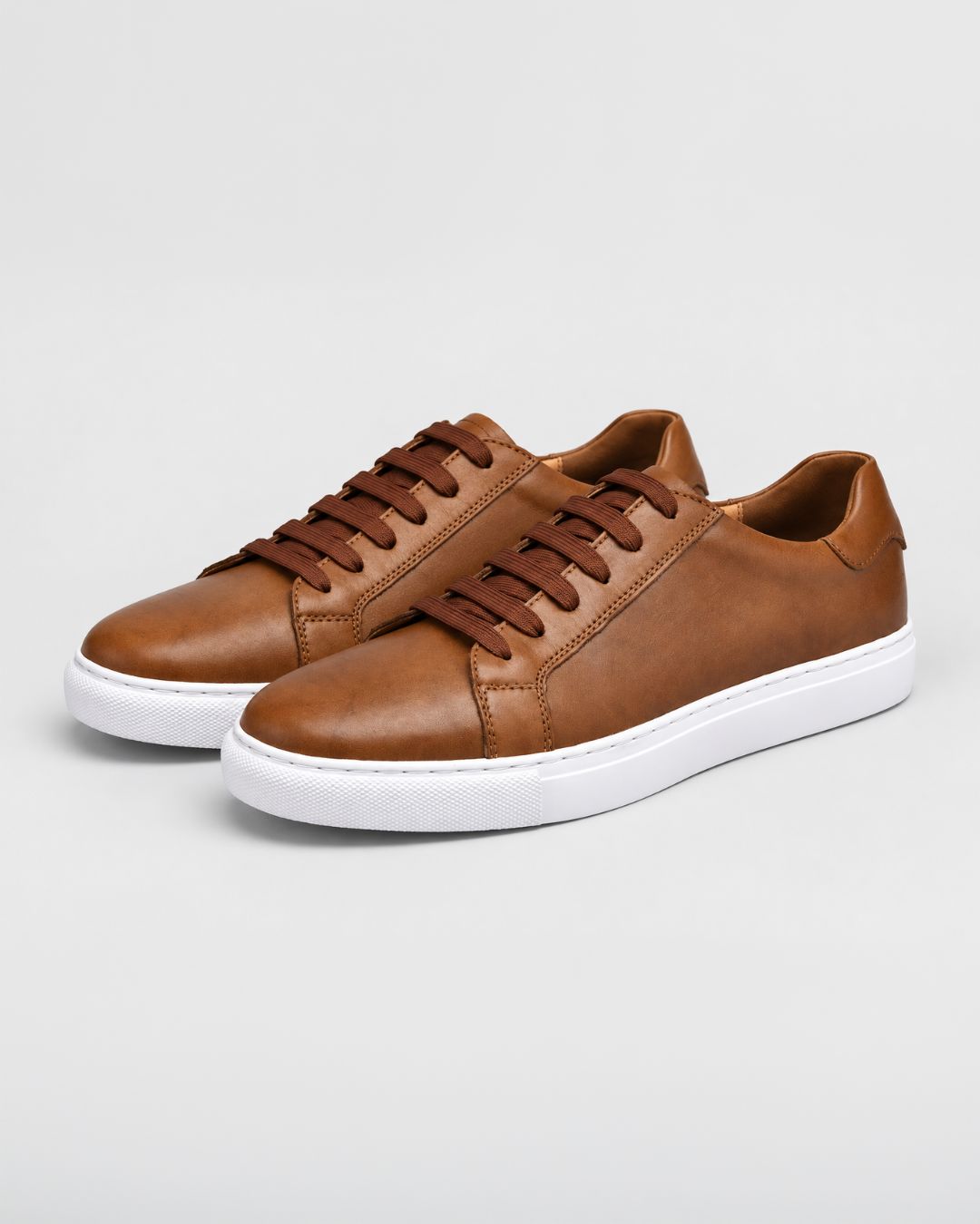 Tan top-grain leather low-top dress sneakers with brown laces and a white rubber outsole.
