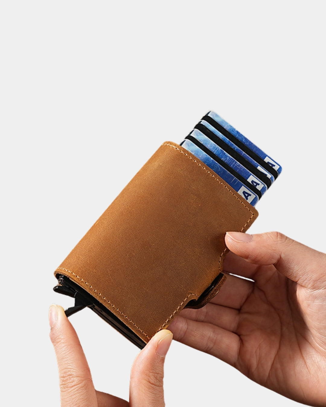 Tan genuine cowhide leather pop-up card wallet held in hand with cards fanned out from the automatic mechanism.