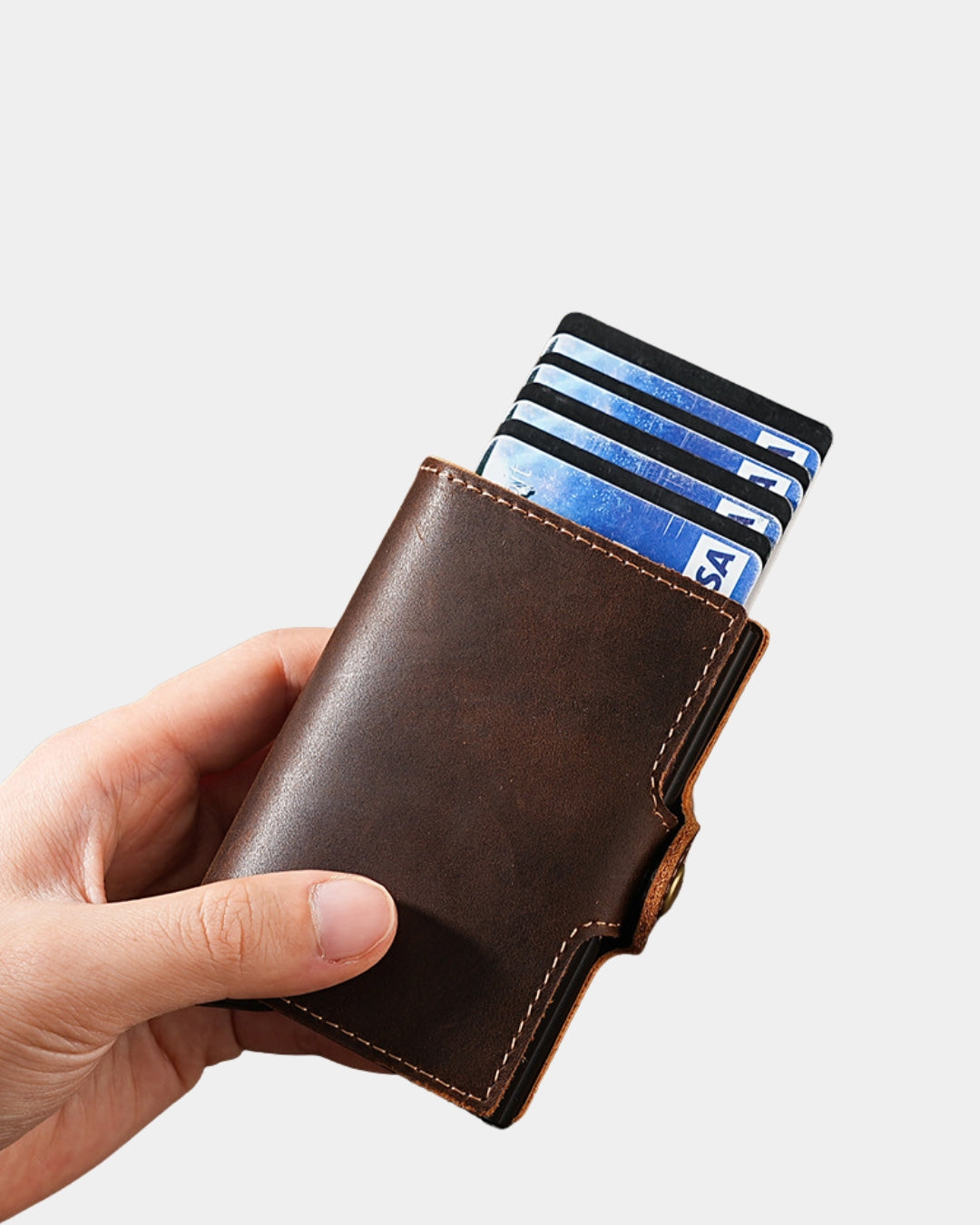 Hand holding a compact brown genuine leather pop-up card wallet with cards fanned out and a secure snap-button closure.