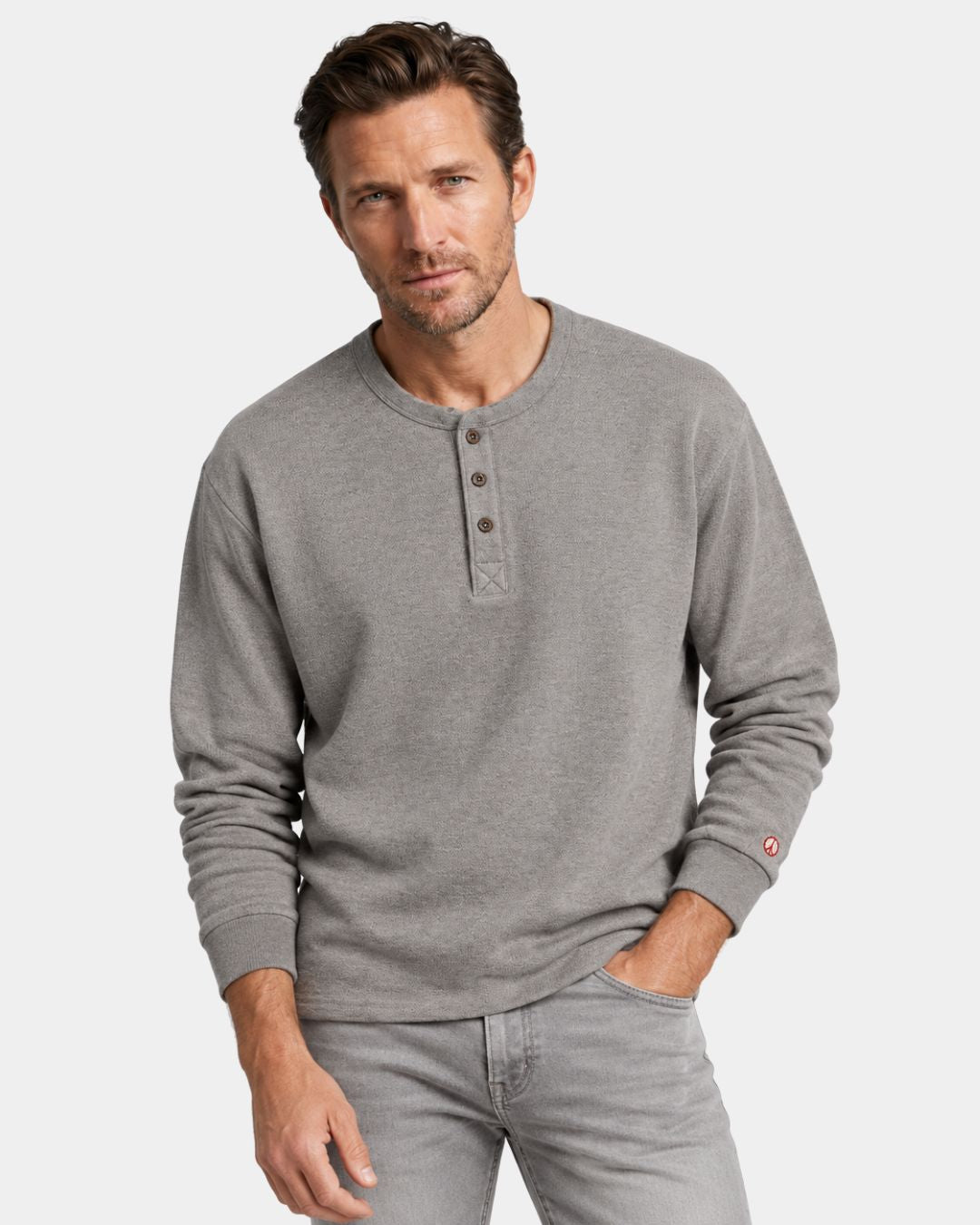 Men’s gray heavyweight cotton long-sleeve henley shirt with a three-button placket and red embroidered peace symbol on cuff.