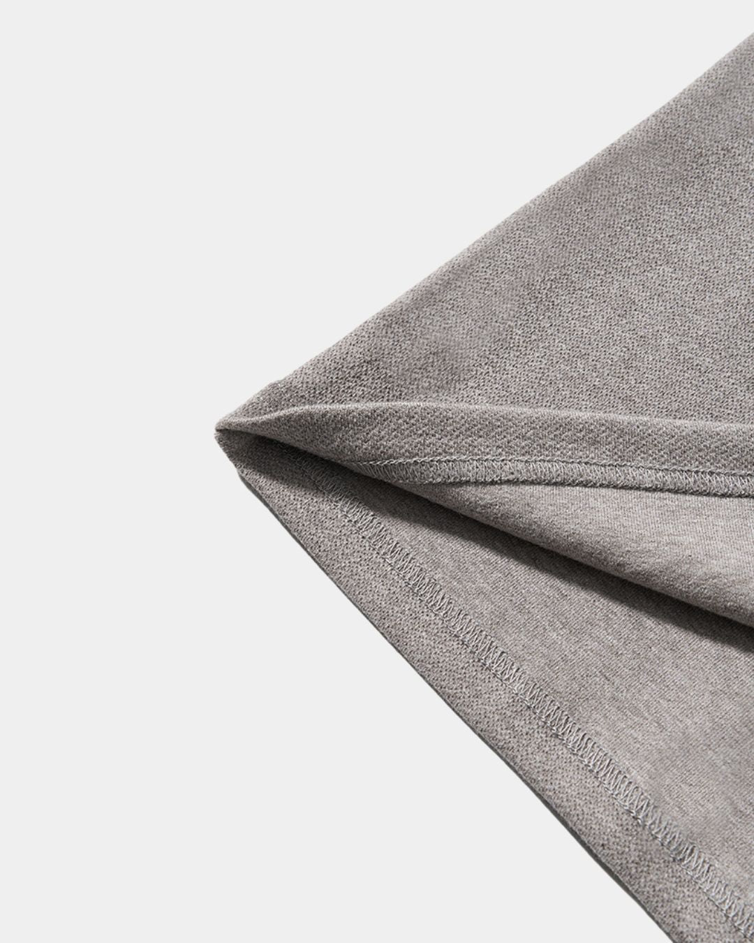 Close-up of the textured gray heavyweight cotton fabric and hem stitching of a men's long sleeve henley shirt.
