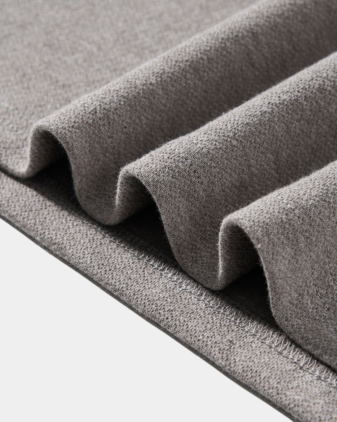 Close-up of thick, gray heavyweight cotton-blend knit fabric with a soft, textured finish and visible stitching.