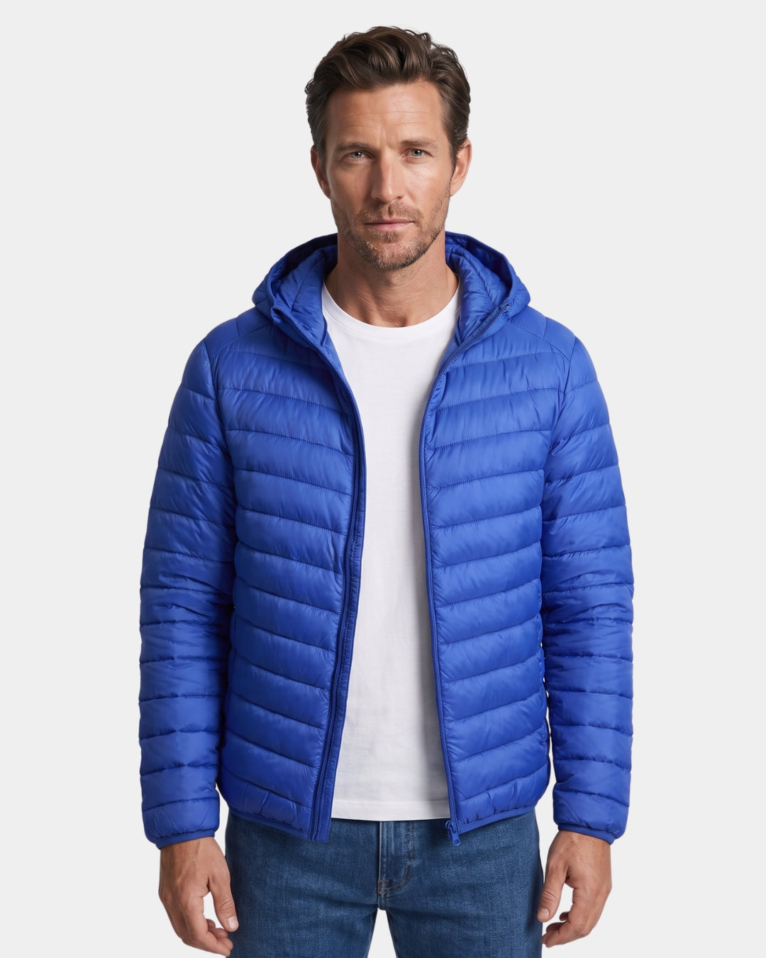 Man wearing a bright blue, lightweight hooded puffer jacket with a quilted design and full-zip front.