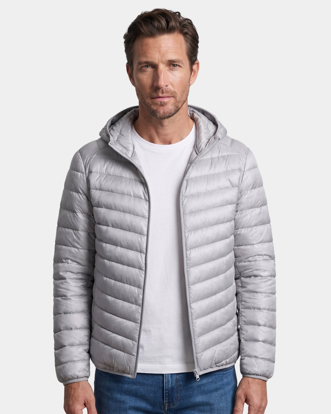 Man wearing a light grey, quilted hooded puffer jacket with a full-zip front and lightweight nylon shell.