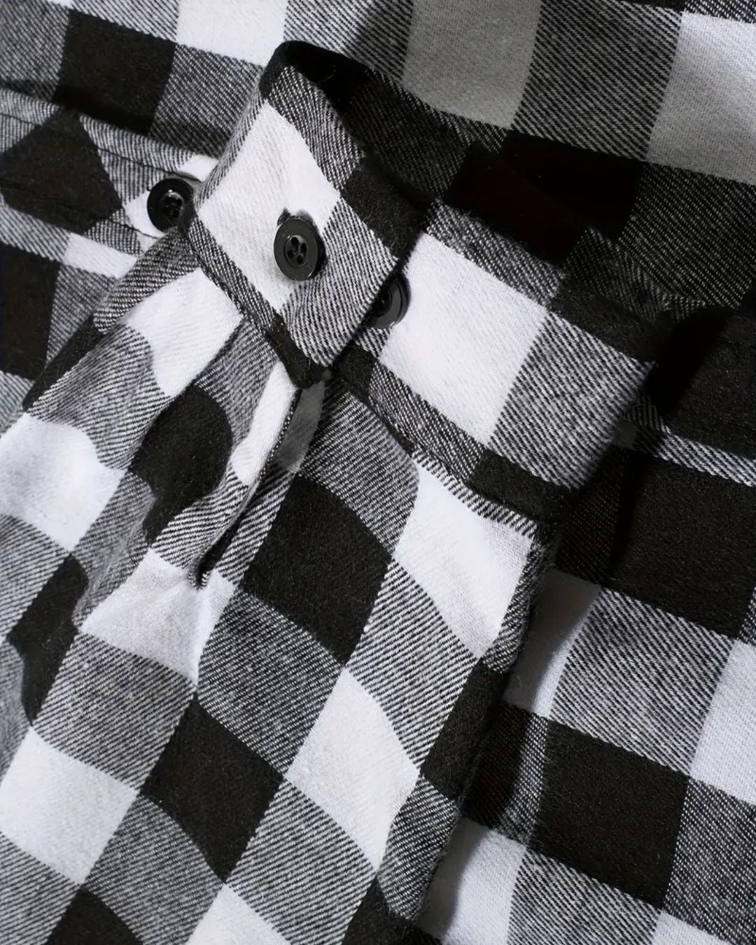 Close-up of a black and white plaid flannel shirt sleeve featuring a buttoned cuff and soft brushed fabric texture.