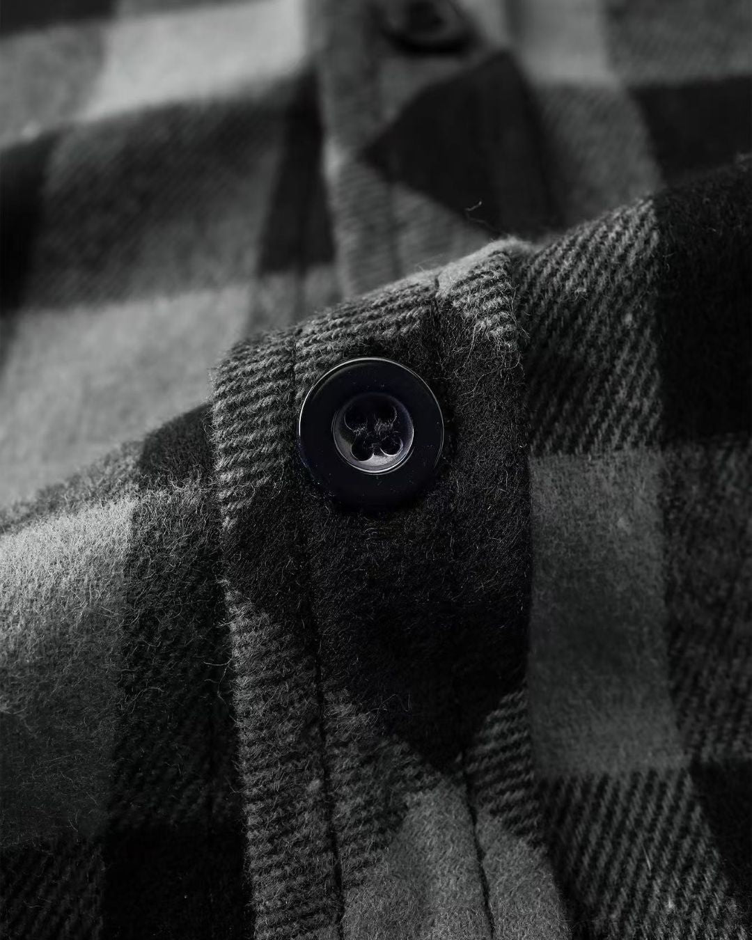Close-up of a soft, black and grey plaid flannel shirt featuring a button-front design and brushed fabric texture.