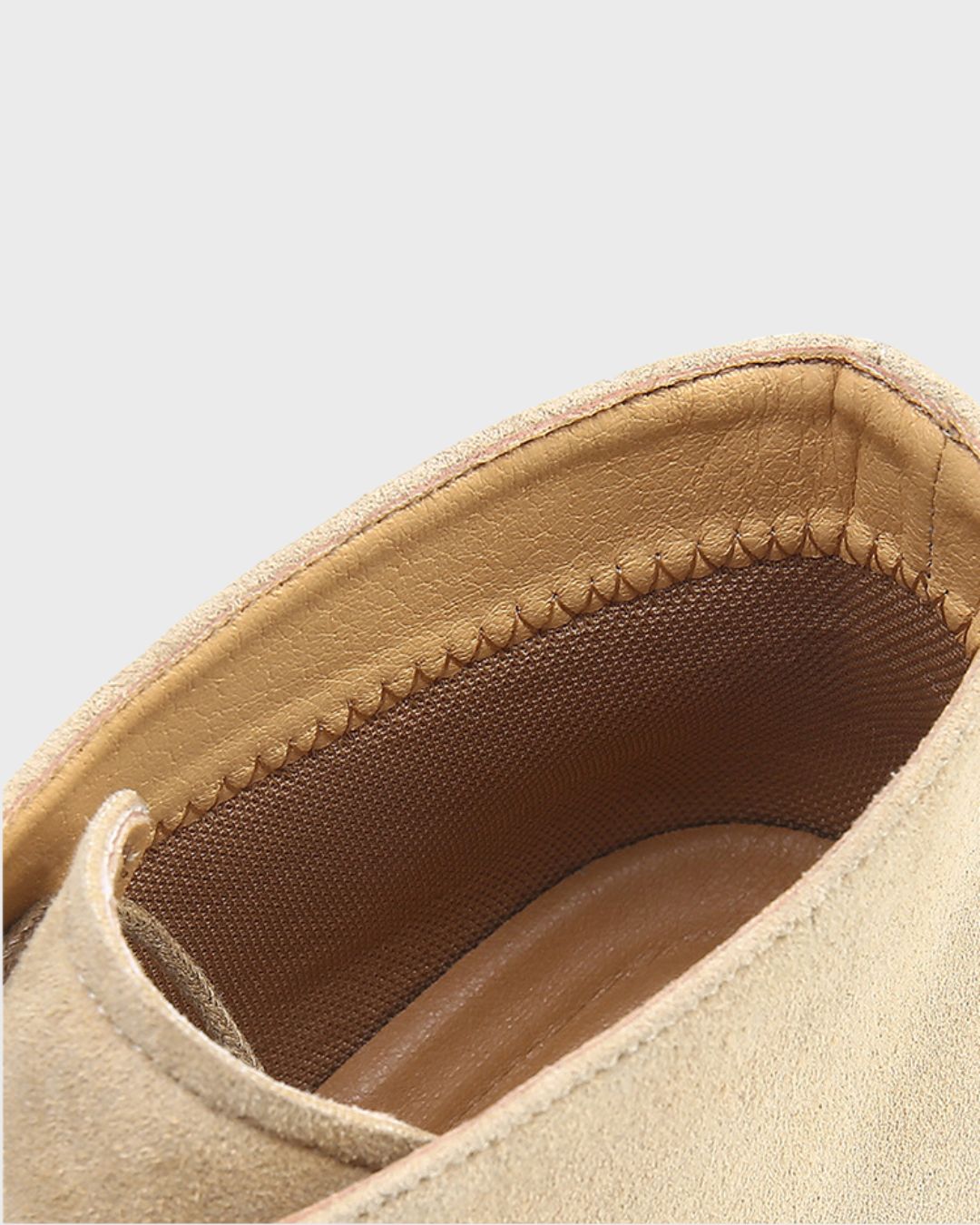 Close-up detail of a beige suede chukka boot interior showing the stitched lining and textured tan insole.