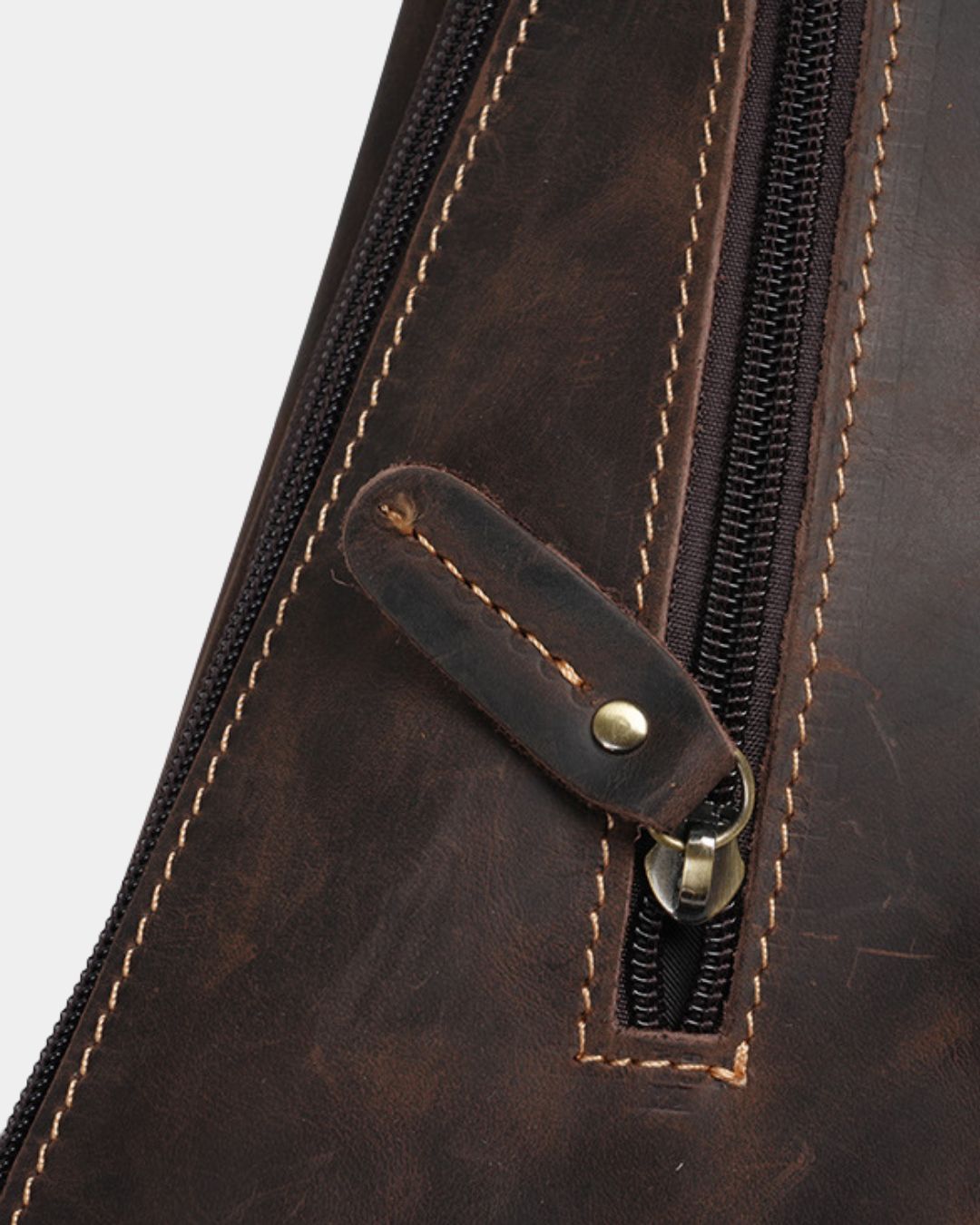 Close-up of a dark brown genuine leather sling bag featuring a vintage finish, sturdy metal zipper, and reinforced stitching.