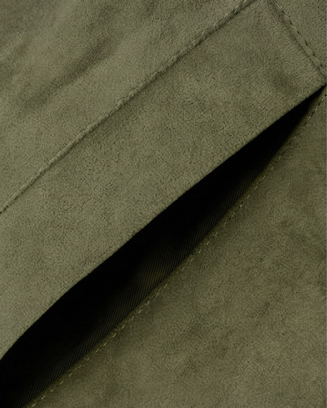 Close-up of an olive green fleece bomber jacket featuring a soft, suede-inspired texture and a side pocket detail.