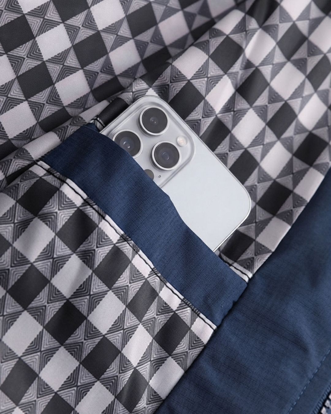 Navy blue Harrington jacket interior with a black and white checked lining and a practical inner pocket holding a phone.