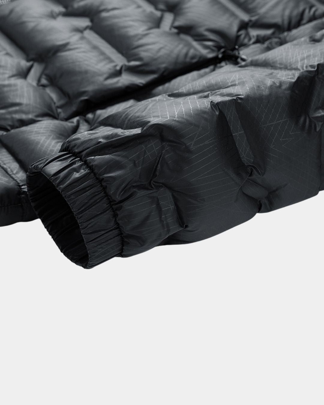 Close-up of a black quilted puffer jacket sleeve featuring a subtle grid pattern and an elasticated cuff.