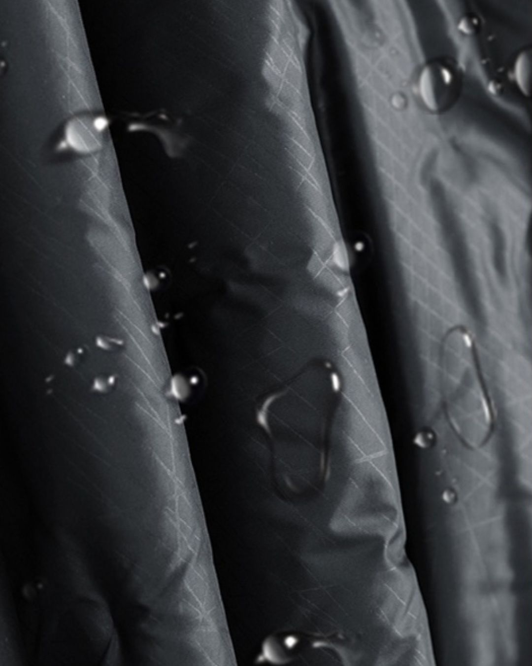 Waterproof black quilted puffer jacket fabric with a grid pattern and visible water droplets.