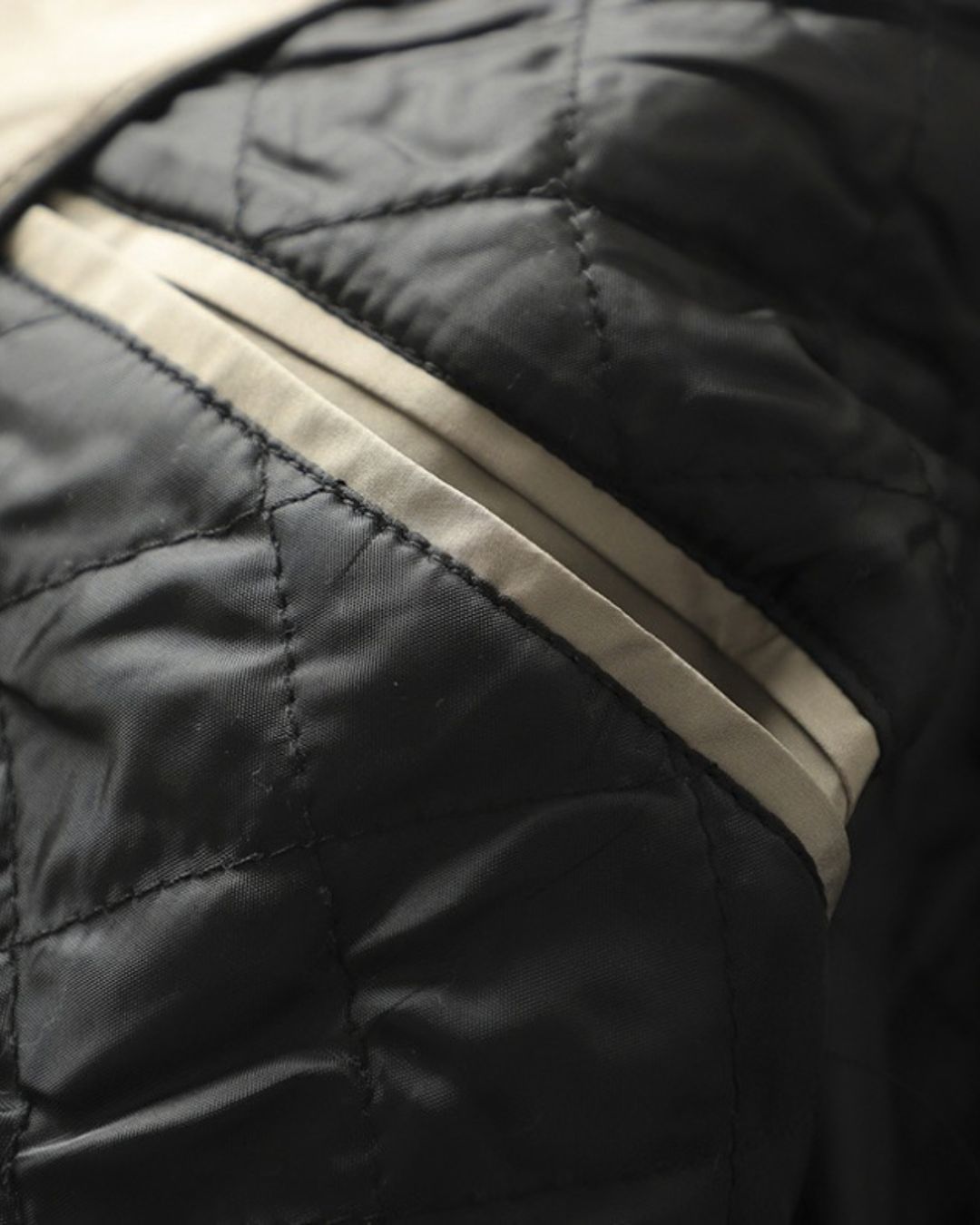 Close-up of a men’s trench coat featuring a black quilted interior lining and beige trim detail.
