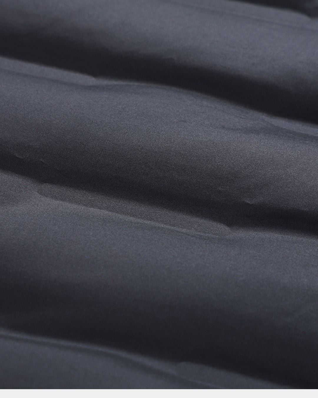 Close-up of a charcoal grey men’s puffer jacket featuring quilted, water-repellent fabric and lightweight down insulation.