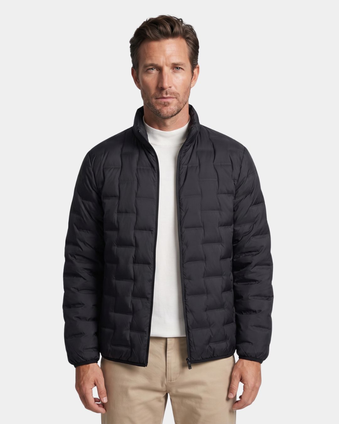 Man wearing a black lightweight quilted down puffer jacket with a stand collar and full-zip front.