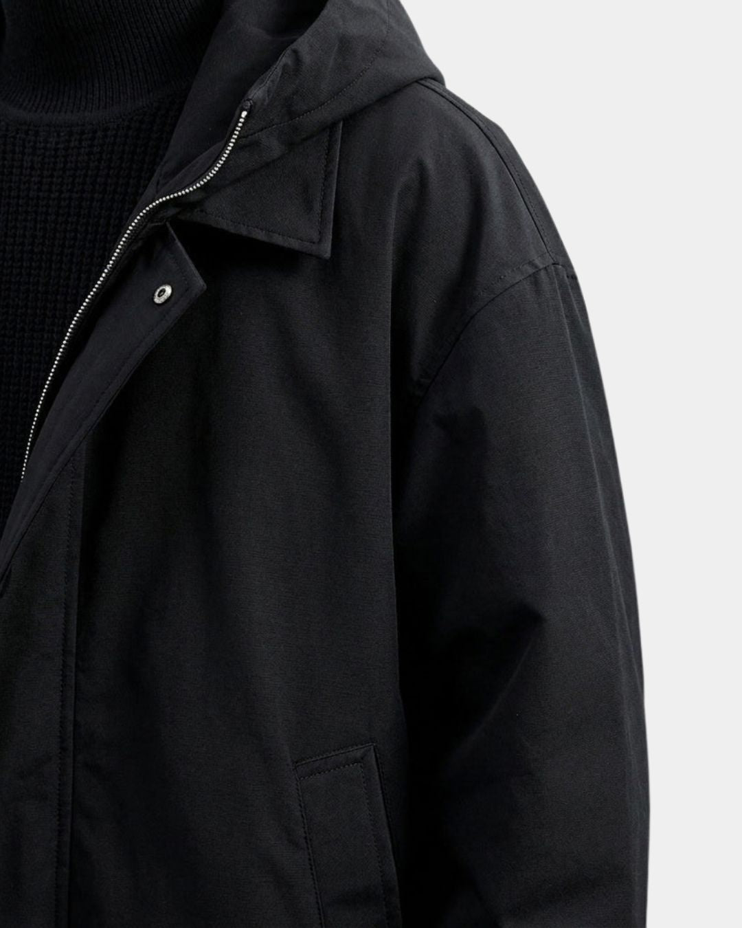 Black men’s hooded overcoat with a windproof finish, full zip, button closure, and a relaxed trench-inspired silhouette.