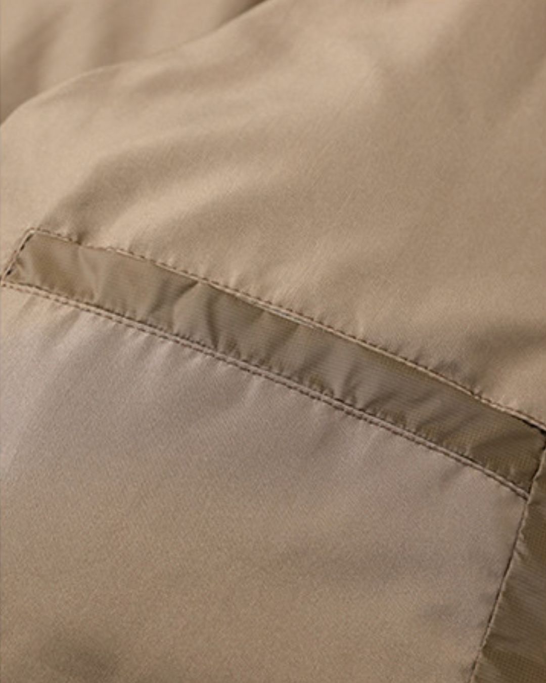 Close-up of a tan men's puffer jacket featuring smooth polyester fabric and a subtle tonal contrast chest panel detail.