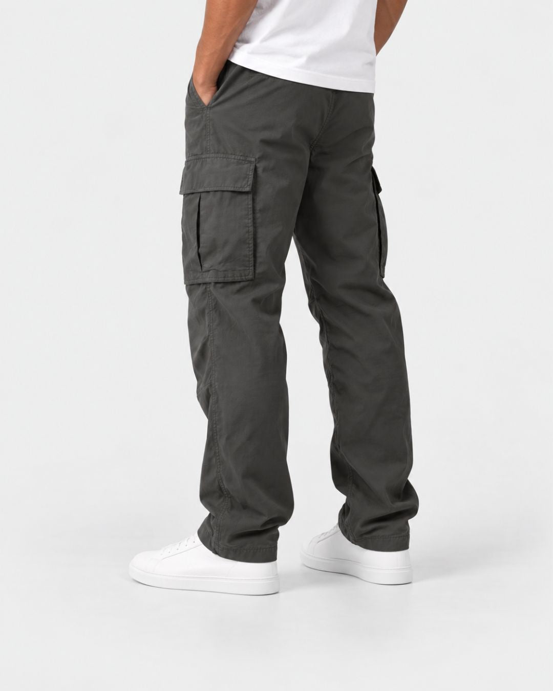 Men’s charcoal relaxed-fit cargo pants with side flap pockets and adjustable drawcord hems, worn with white sneakers.