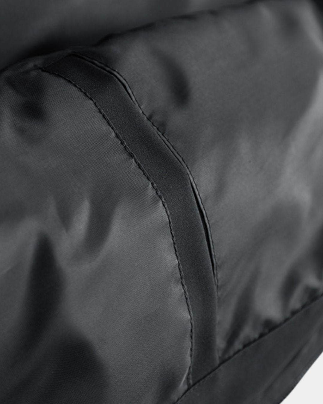 Close-up of a black men’s utility jacket featuring smooth, water-resistant contrast panels and reinforced stitching.