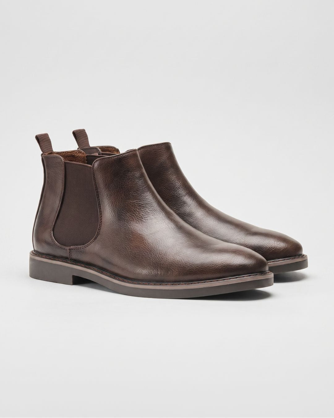 Pair of black leather Chelsea boots on a light gray background