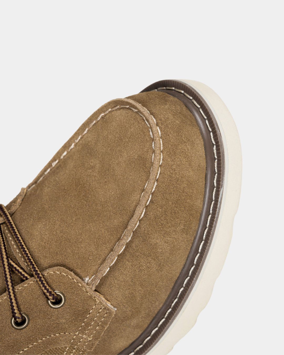 Tan suede moc toe ankle boot with contrast stitching, metal eyelets, and a chunky white rubber outsole.