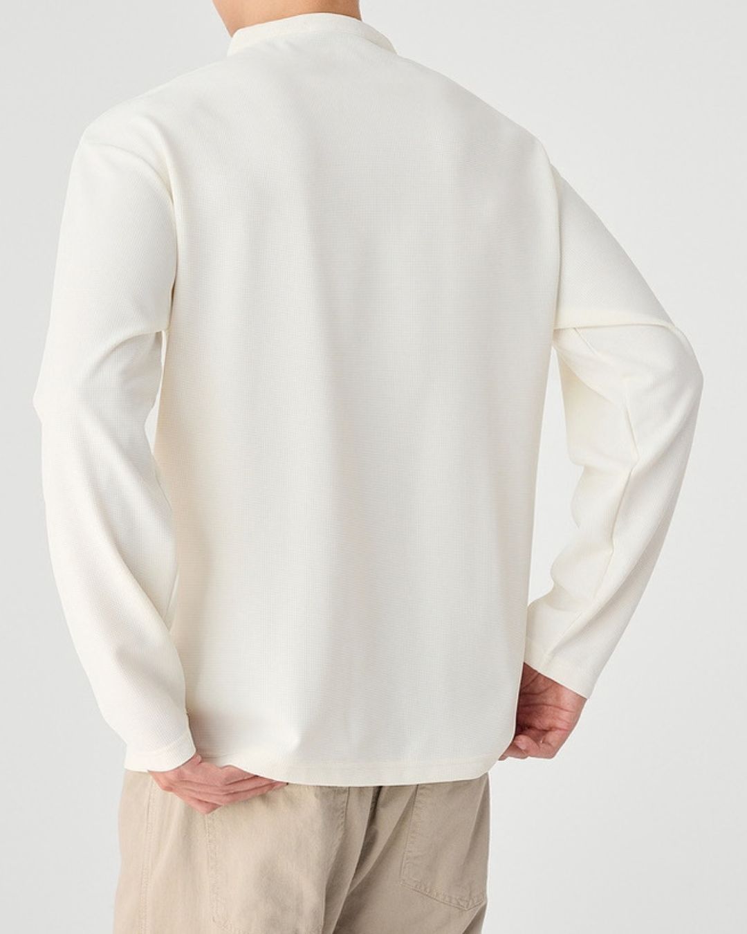 Back view of a white men’s long sleeve henley shirt featuring a textured waffle knit and relaxed dropped shoulders.