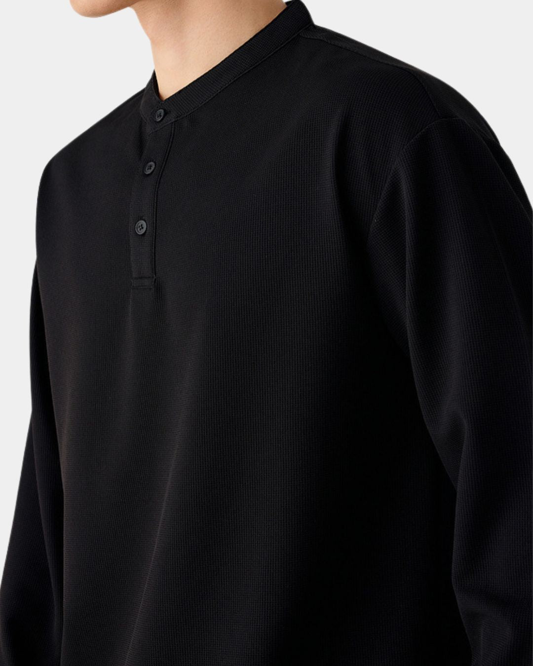 Black long-sleeve henley shirt in a textured waffle knit with a band collar and three-button placket.