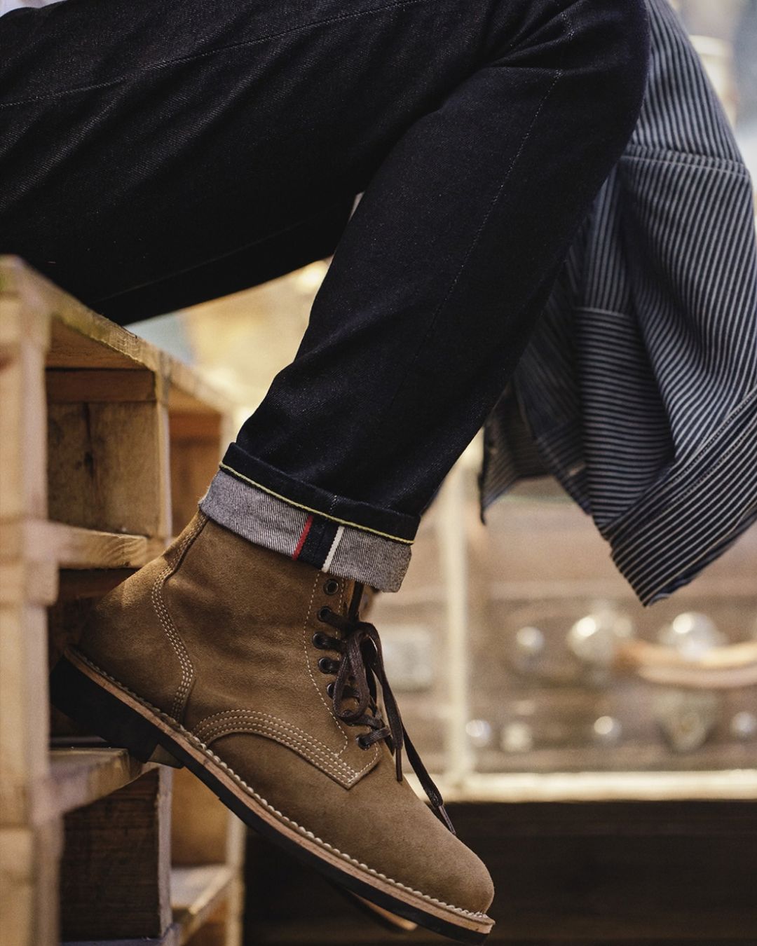 Men’s tan suede lace-up ankle boots with contrast stitching, round toe, and durable rubber outsole worn with cuffed denim.