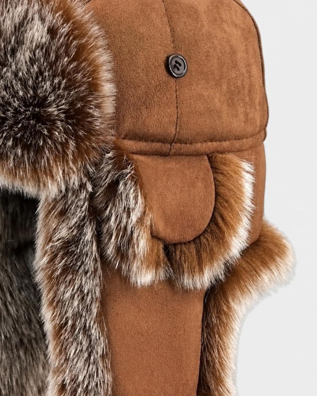 Brown suede ushanka trapper hat with plush faux fur lining and button-down ear flaps for winter warmth.