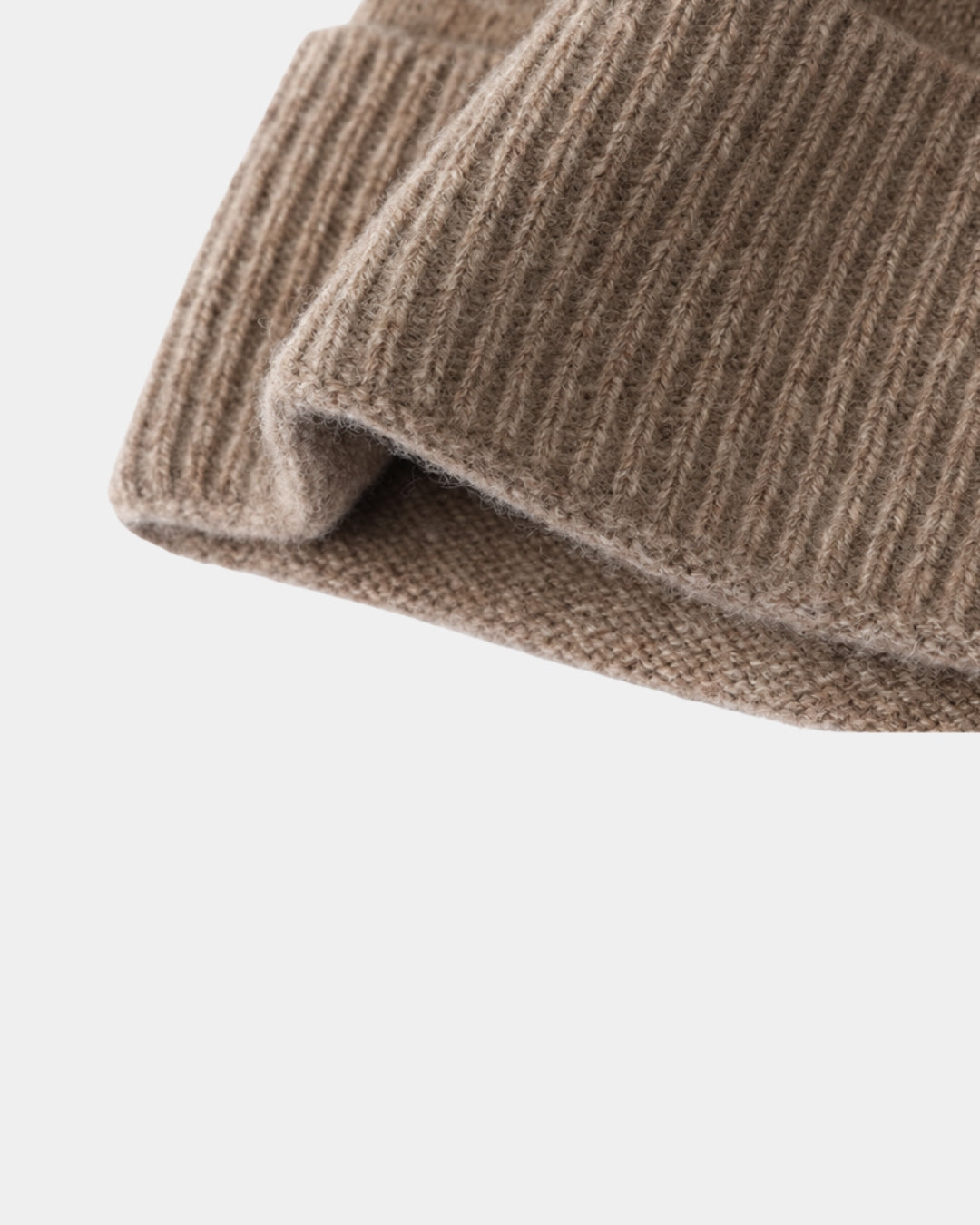 Close-up of a tan wool cuffed beanie featuring a soft, ribbed knit texture and a classic fold-over design.