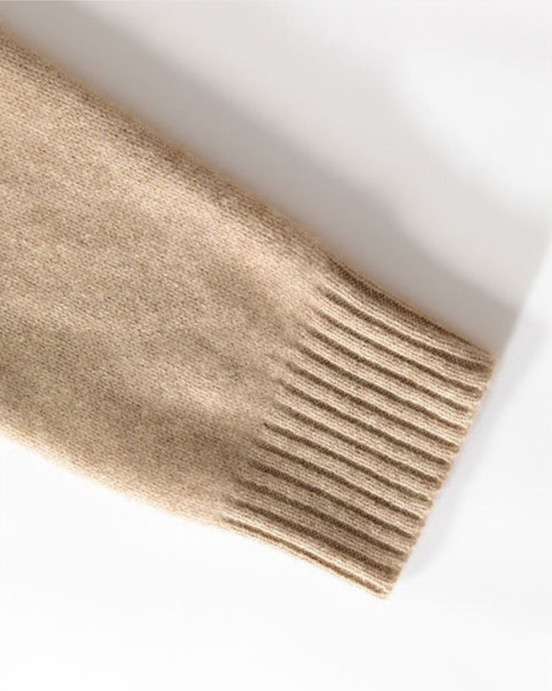 Beige wool knit sweater sleeve featuring a textured diamond pattern and a ribbed cuff.