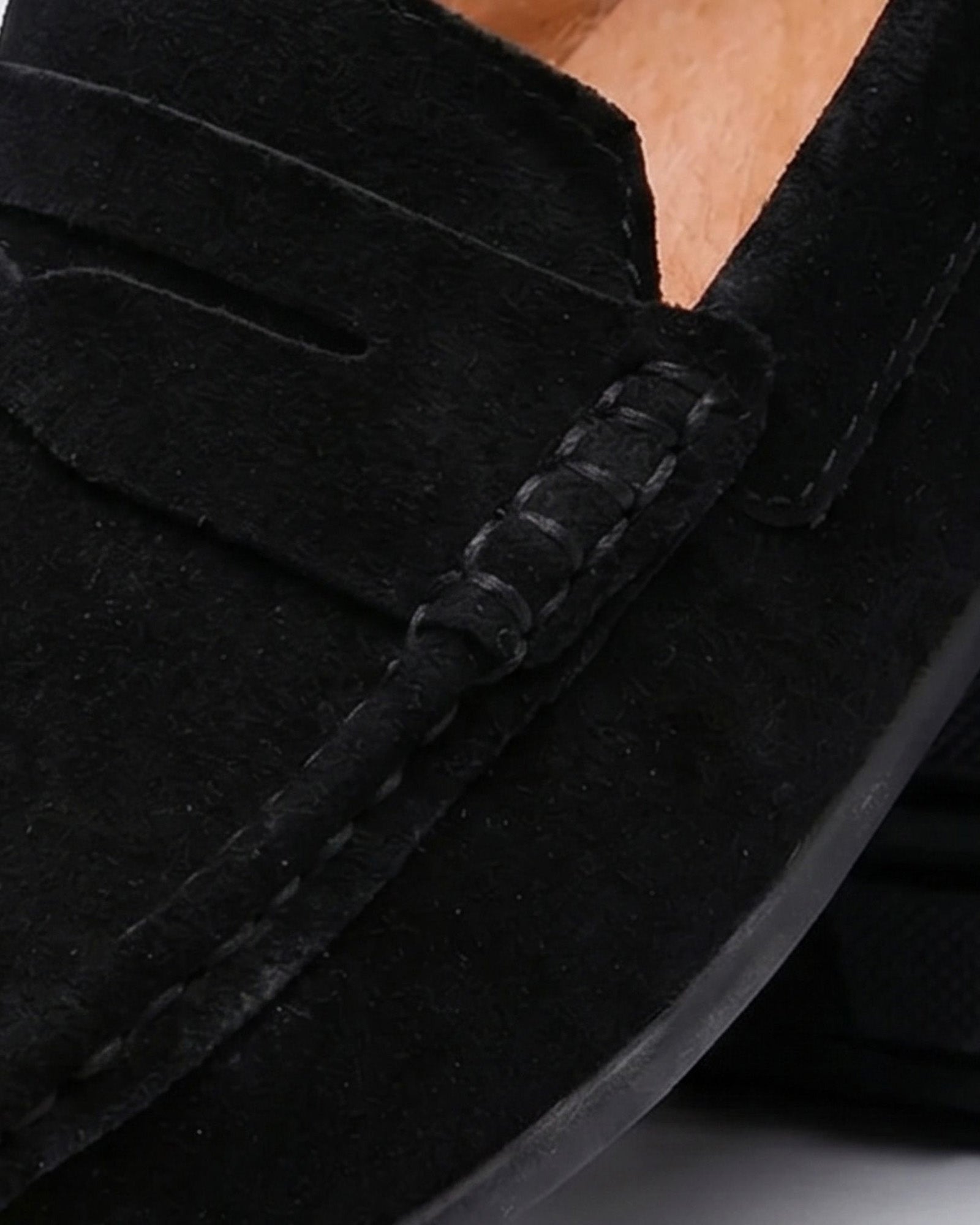 Close-up of Nigel men's black suede driving loafer showing penny strap and saddle stitching detail