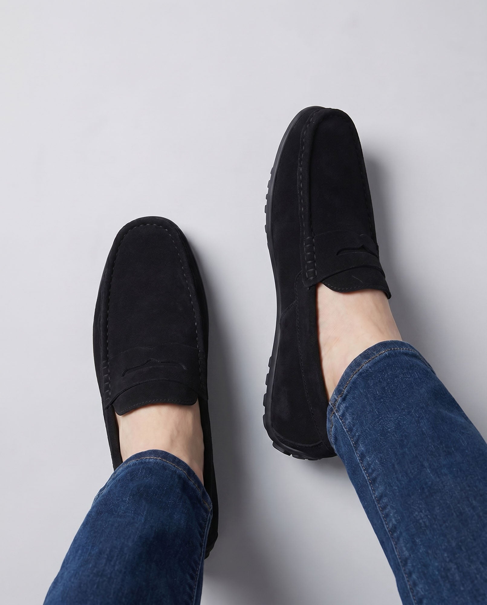 Overhead view of Nigel men's black suede driving loafers worn with blue denim jeans