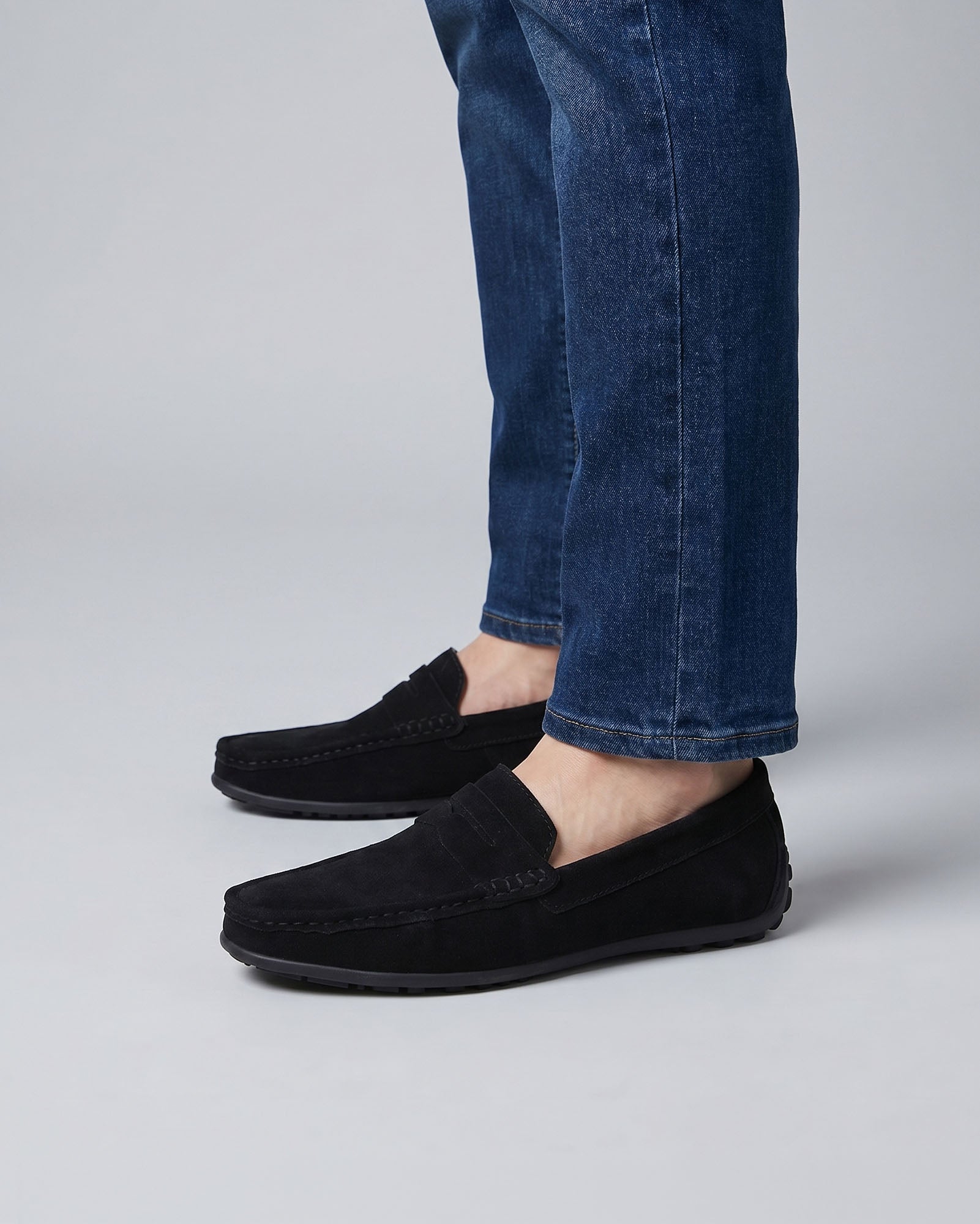 Nigel men's black suede driving loafers worn side-on with blue denim jeans