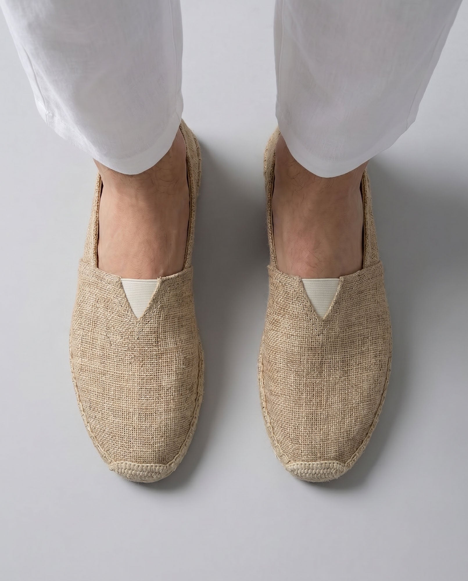 Overhead view of Tulum men's beige canvas espadrille loafers worn with white trousers