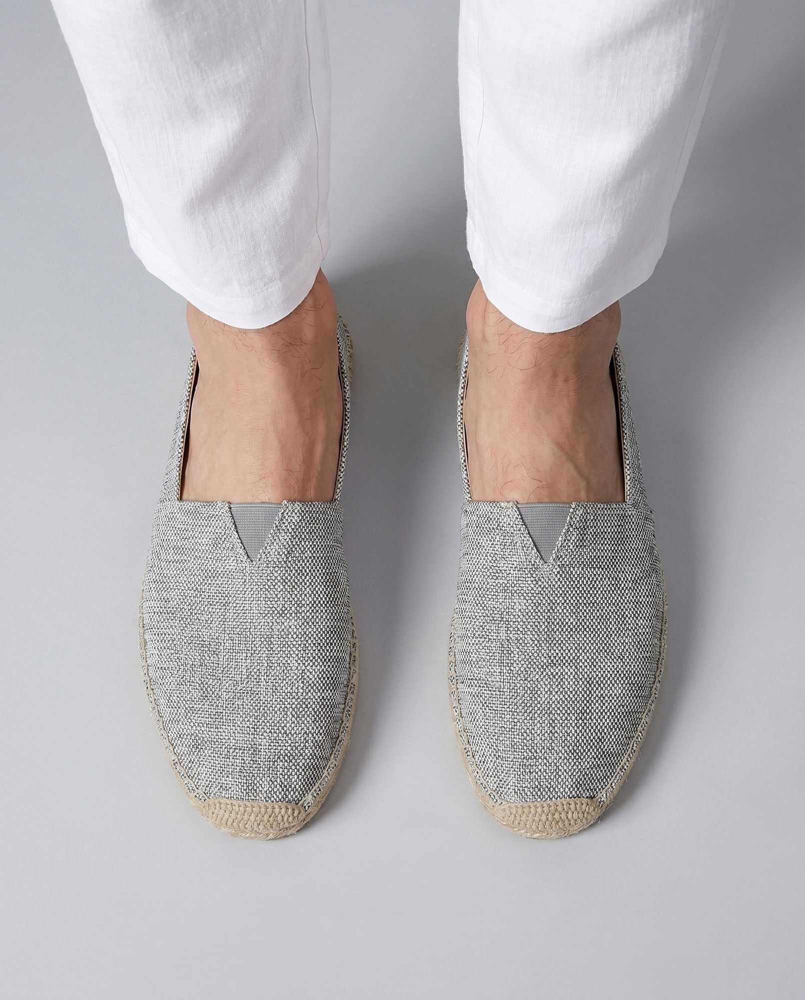 Overhead view of Tulum men's gray canvas espadrille loafers worn with white trousers